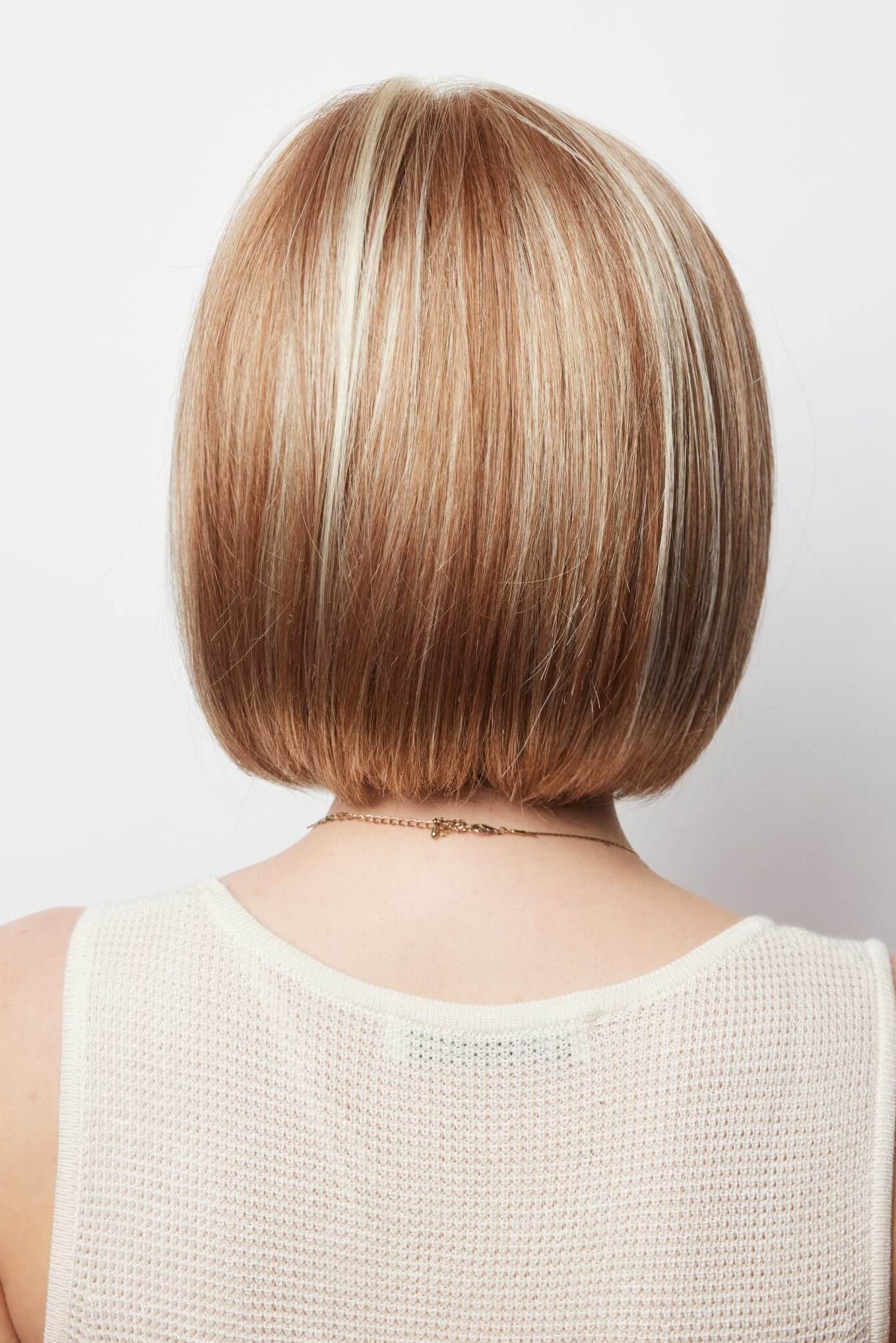 Back view of Erika wig by Amore in Strawberry Swirl – a collar length bob style made with a double mono cap construction.