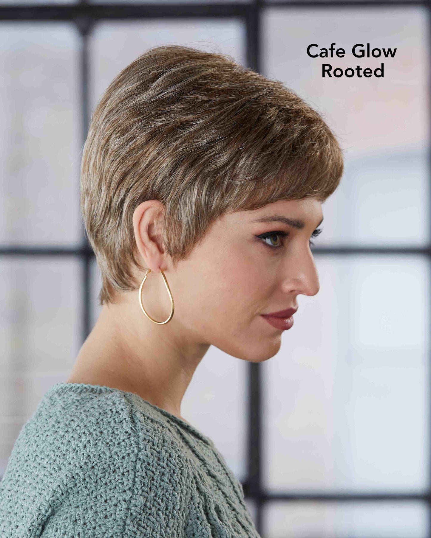 Woman with styled hair, wearing a green sweater and gold hoop earrings, with text 'Cafe Glow Rooted' on a blurred background.