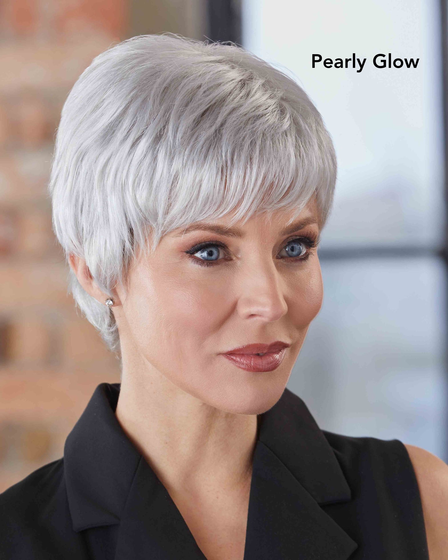 Woman with short, grey styled wig wearing a black top in an indoor setting.