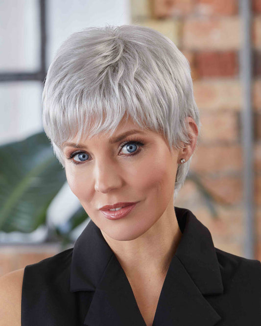 Woman with short grey wig wearing a black outfit indoors.