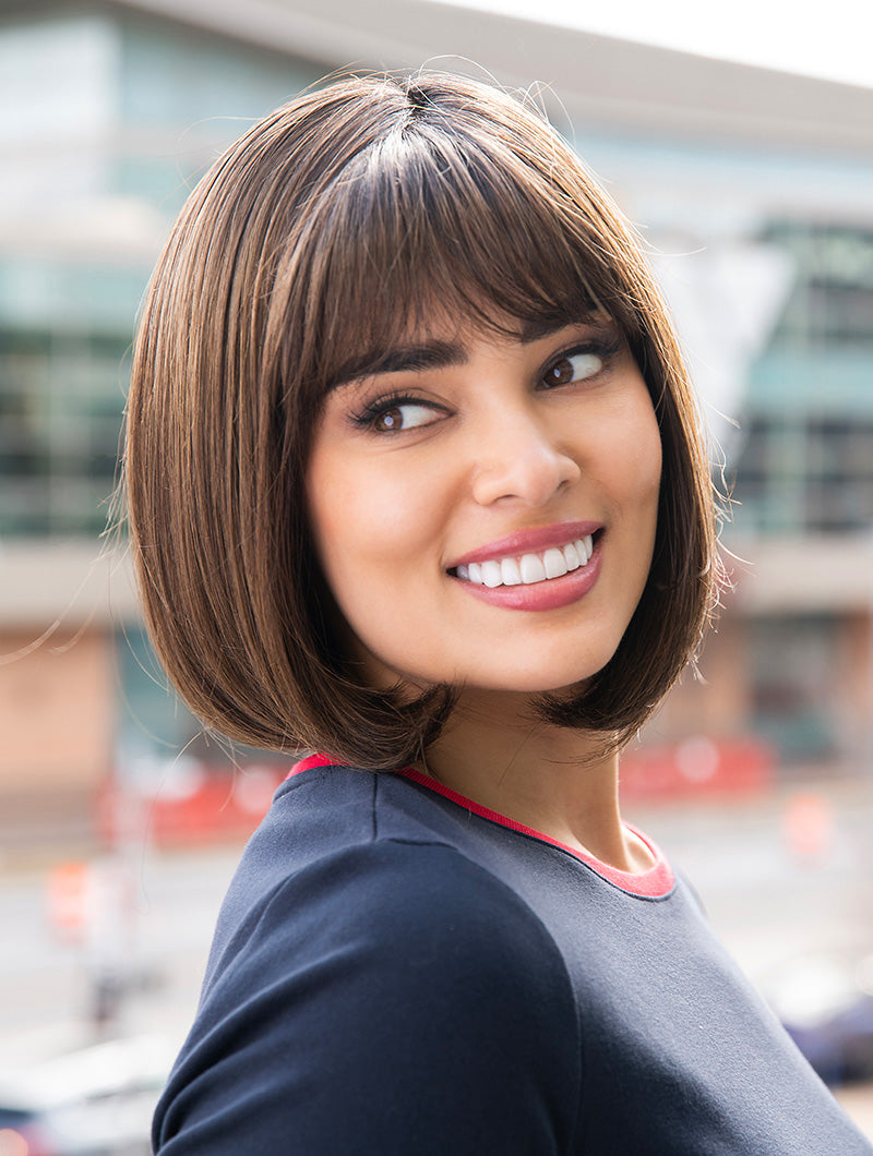 Front view Carley wig by Envy in rooted brunette – face-framing layers, wispy fringe and natural movement with mono top construction