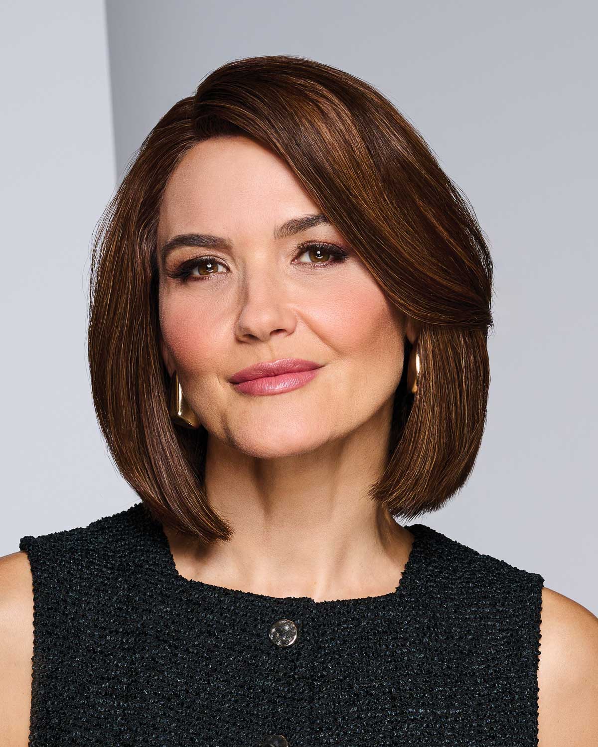 Woman with a bob haircut wearing a black top against a gray background