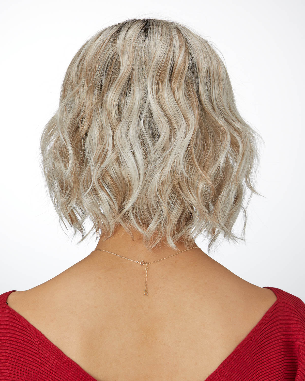 Back view of a person with wavy, shoulder-length hair wearing a red top on a white background